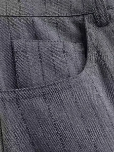 Detail of dark gray striped suit pants showing waistband and precise pocket stitching