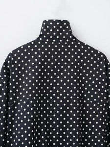Detailansicht des Stehkragens und des schwarzen Punktmusters auf der Pufferjacke