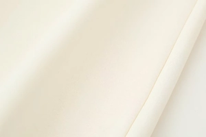 Gros plan du tissu blanc crème montrant sa texture tissée lisse et sa haute qualité