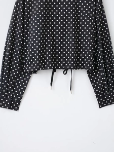 Detail der schwarzen gepunkteten Jacke mit verstellbarem Kordelzugsaum und strukturiertem Stoff