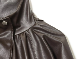 Detail view of brown faux leather bomber jacket with pleated shoulder and silver snap button