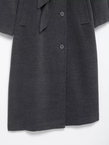 Detail of dark charcoal wool coat showing fabric texture, waist belt and buttons