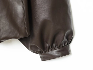 Close-up of the gathered cuffs and textured dark brown faux leather on the bomber jacket