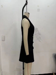 Side view of black sleeveless blazer dress with peak lapels and tailored flap pockets