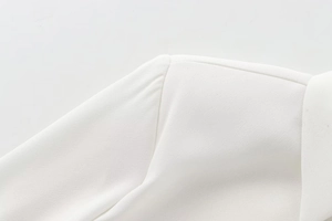 Detailed view of padded shoulder and woven texture on a white long-sleeve blouse