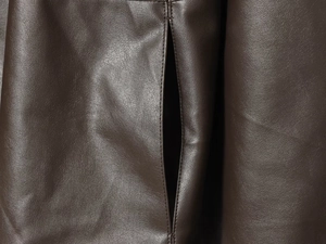 Detail of dark brown leather jacket showing fine stitching and natural grain texture