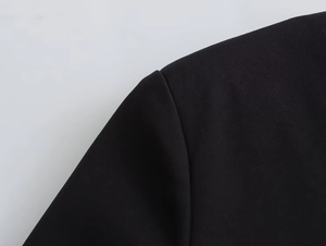 Detailed close-up of smooth black woven fabric and neat stitching on shoulder seam