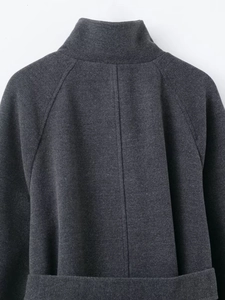 Detail view of charcoal grey high neck coat with raglan sleeves and twill fabric texture