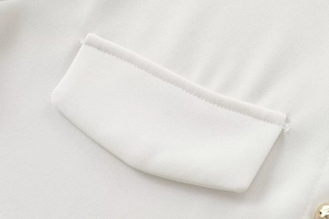 Detailed macro view of white textured woven fabric with clean stitching and gold button
