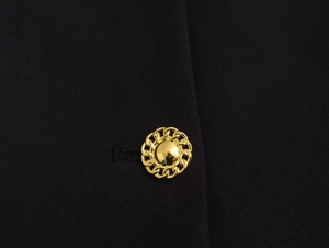 Detail of elegant gold button on black fabric with intricate chain link texture