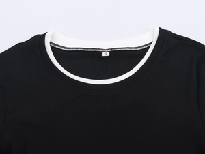 Détail de la maille côtelée noire et de l'encolure ronde contrastée blanche avec étiquette