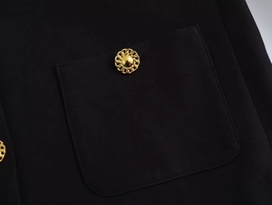 Close-up of golden vintage button with chain texture on black woven fabric pocket