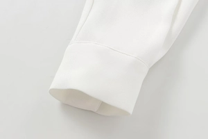 Detailed close-up of white crepe fabric shirt cuff with precise stitching and refined texture