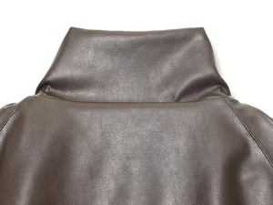 Close-up of high stand collar and fine leather texture on dark brown pilot jacket