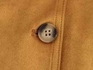 Macro shot of brown faux suede blazer with detailed marble-textured button and neat stitching