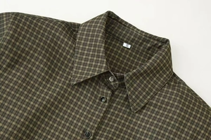 Detailed close-up of dark green and yellow plaid shirt with size S tag and resin buttons