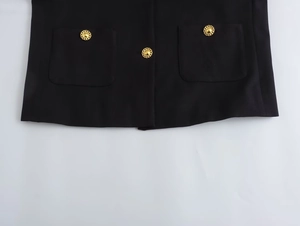 Detail of black jacket featuring vintage gold buttons and symmetrical square pockets