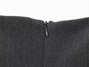 Détail d'une fermeture éclair invisible sur un tissu gris foncé à texture fine