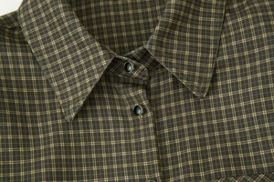 Macro view of dark plaid shirt collar with detailed black and silver round buttons