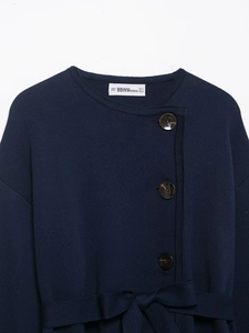Close-up of navy knit cardigan with belt detail and woven brand label on neckline