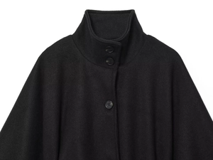 Close-up of black high-neck wool poncho jacket featuring a double-button closure detail