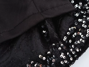 Macro detail of black knit dress with sequin trim and suede texture finish