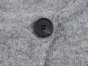 Detailed macro shot of grey knitted wool coat with a marble-textured black button fastener