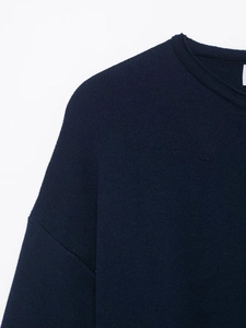 Detail of navy knit coat neckline featuring ribbed collar and fine fabric texture