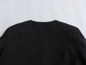 Detail shot of black textured round neck jacket showing seamless shoulder and collar seams