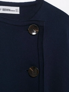 Detail shot of navy knit jacket featuring large tortoiseshell buttons and branded collar label