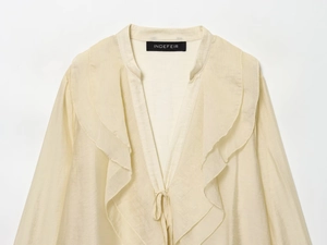 Close-up of v-neck cream chiffon blouse with double ruffle detailing and neckline ties