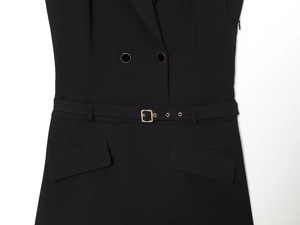 Close-up of black blazer dress featuring a waist belt with gold buckle and flap pockets