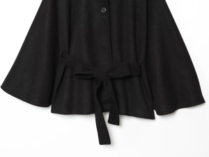 Detail of black wool cape coat showing waist belt with bow and single round button