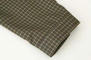 Macro shot of plaid long-sleeve cuff with fine stitching on olive green fabric
