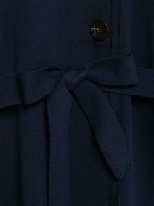 Detail of navy knit coat showing belted waist with a bow and smooth brown button