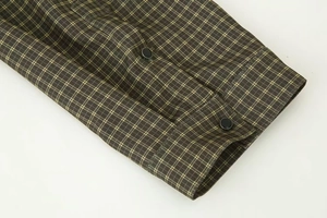 Detail of plaid shirt cuff with double black buttons on yellow grid woven fabric