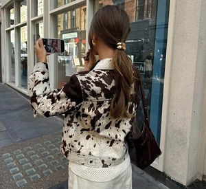 Dettaglio giacca corta stampa mucca con accessorio per capelli dorato e stile urban