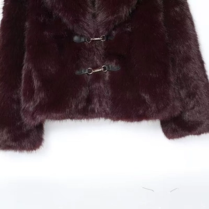 Détail d'une veste en fausse fourrure bordeaux avec grand col et boucles en métal sur cuir
