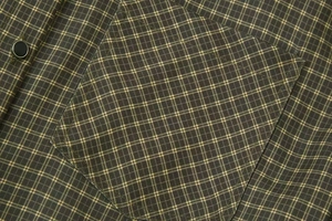Close-up of chest pocket and metal button on green plaid padded shoulder shirt