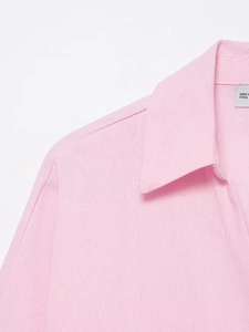 Dettaglio ravvicinato del colletto della camicia rosa con texture e etichetta