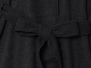 Close-up of a black wool poncho coat featuring a waist belt tied in a neat bow knot