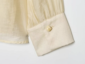 Detailed close-up of textured chiffon sleeve with elegant gold-rimmed marble button