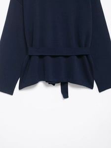 Detail of navy blue knit cardigan featuring a matching waist belt and fine fabric texture