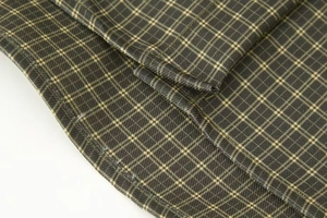 Detail of dark green and yellow plaid fabric with neat stitching on a cotton shirt