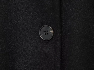 Macro view of a marble-textured button on a black high-collar loose cape coat