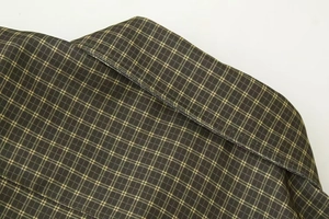Detailed macro view of dark green plaid shirt fabric with yellow and white woven texture