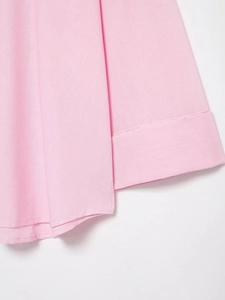 Dettaglio ravvicinato della trama del tessuto rosa e cuciture fini su una camicia