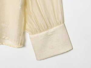 Detailed close-up of pleated cuff design on light beige chiffon shirt for women