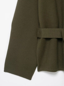 Detail of dark olive green knit coat featuring a matching tie belt and fine texture