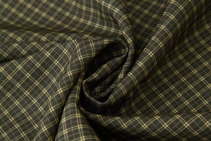 Detailed close-up of dark green plaid fabric texture with yellow grid pattern